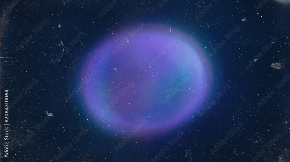 Fototapeta premium Circular purple and blue nebula lens flare on grainy dark background.