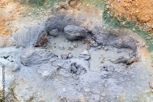 small puddle of boiling mud emits steam in Seltun, a geothermal area in Reykjanes Peninsula in Iceland on a spring day