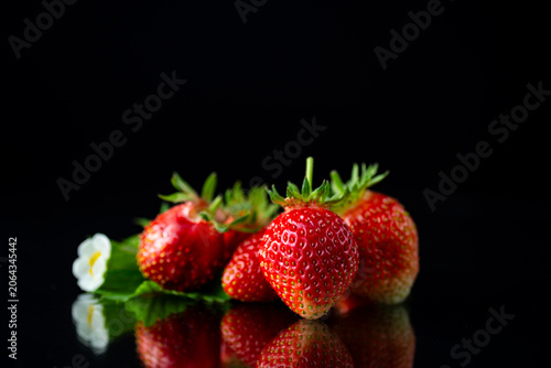 Fresh ripe strawberries with reflection on black background