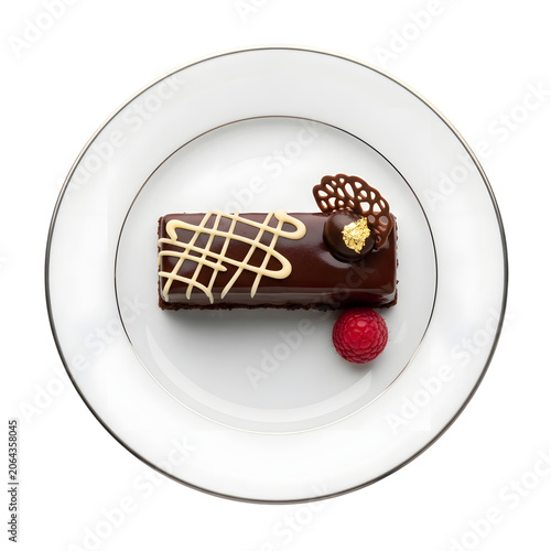 Elegant chocolate mini cake with white and dark chocolate drizzle, gold leaf, and fresh raspberry on a white plate, top view.