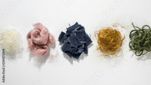Textiles of varying colors and textures are arranged in a horizontal row against a bright white background.
