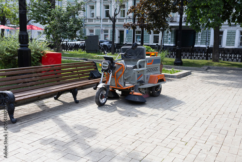 Compact electric street sweeper machine parked on city pavement, urban maintenance and public utility service