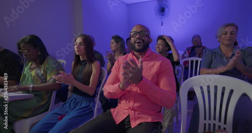 Tableau sur toile Man in bright shirt claps during church service as congregation around him engag