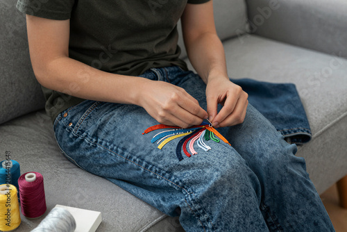 Person Embroidering Rainbow Pattern on Denim Jeans