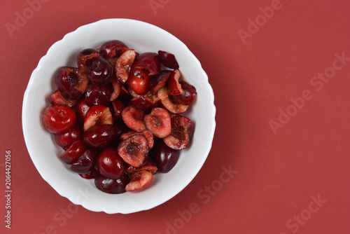 Fotografie Top view of fresh juicy sweet cherries cut in half with pits removed in a white