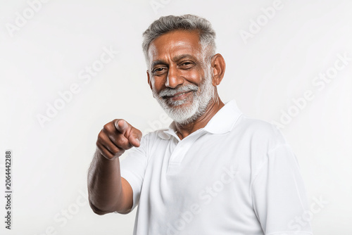 Portrait of a smiling senior South Asian male coach pointing finger at camera on white background