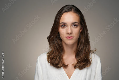 Portrait of a beautiful young woman with long brown hair and brown eyes looking