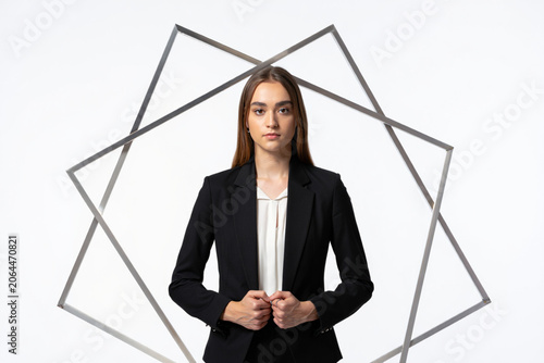Serious businesswoman in black suit and white blouse, geometric frame, studio