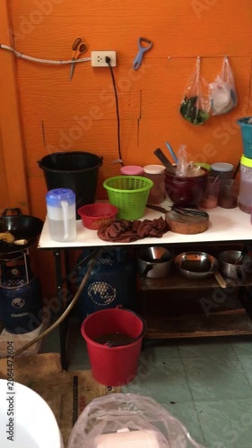 A panning shot of the cooking area of a Thai restaurant in Bangkok showing various utensils, cookware and ingredients. 