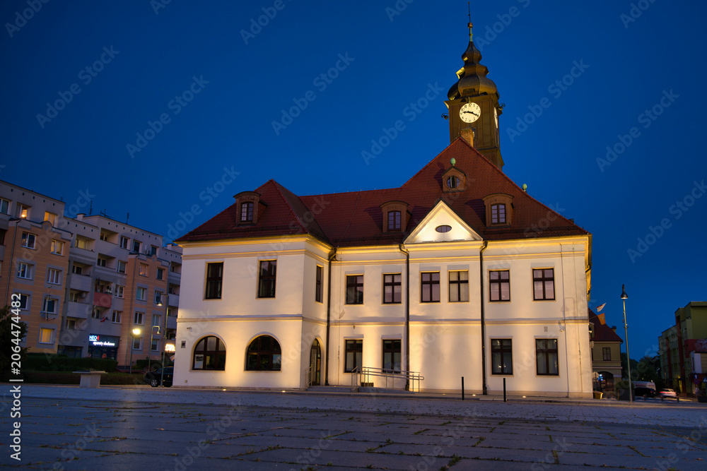Fototapeta premium Historic Town Hall With Clock Tower Over Quiet Urban Square At Sunset - City Of Lubin.