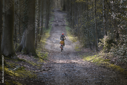 Adult and child ride mountain bikes through the forest