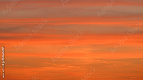 A relaxing scene with medium-level altostratus clouds, tinged with reddish-orange hues in the evening sky. 