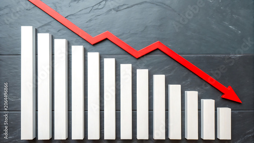 A white bar chart showing a downward trend with a red arrow pointing down against a dark gray slate stone background, representing economic loss