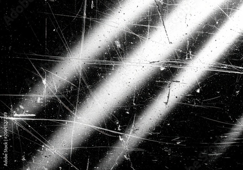 Scratched surface with diagonal light beams and dust particles on black background during day