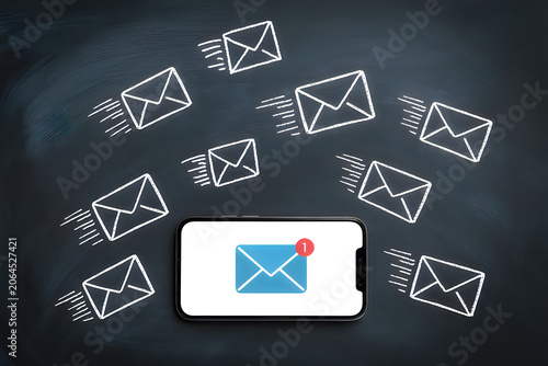 Smartphone receiving many email notifications on a chalkboard background with a concept of digital communication and connectivity