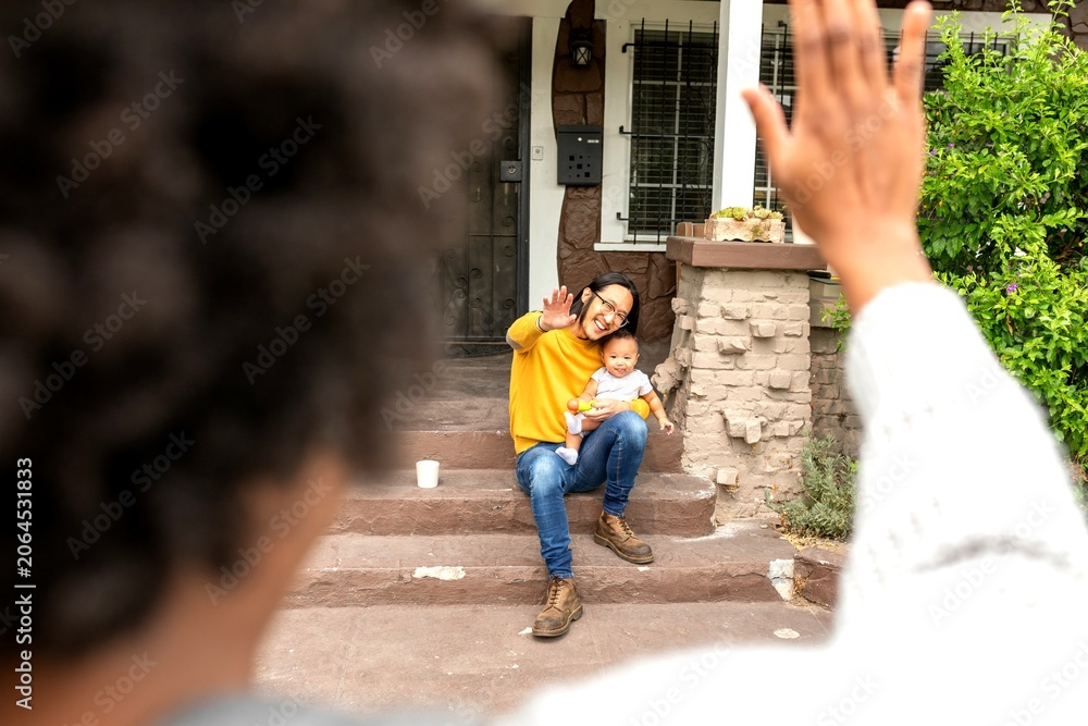 Obraz premium Person waves goodbye to woman with baby on porch steps.