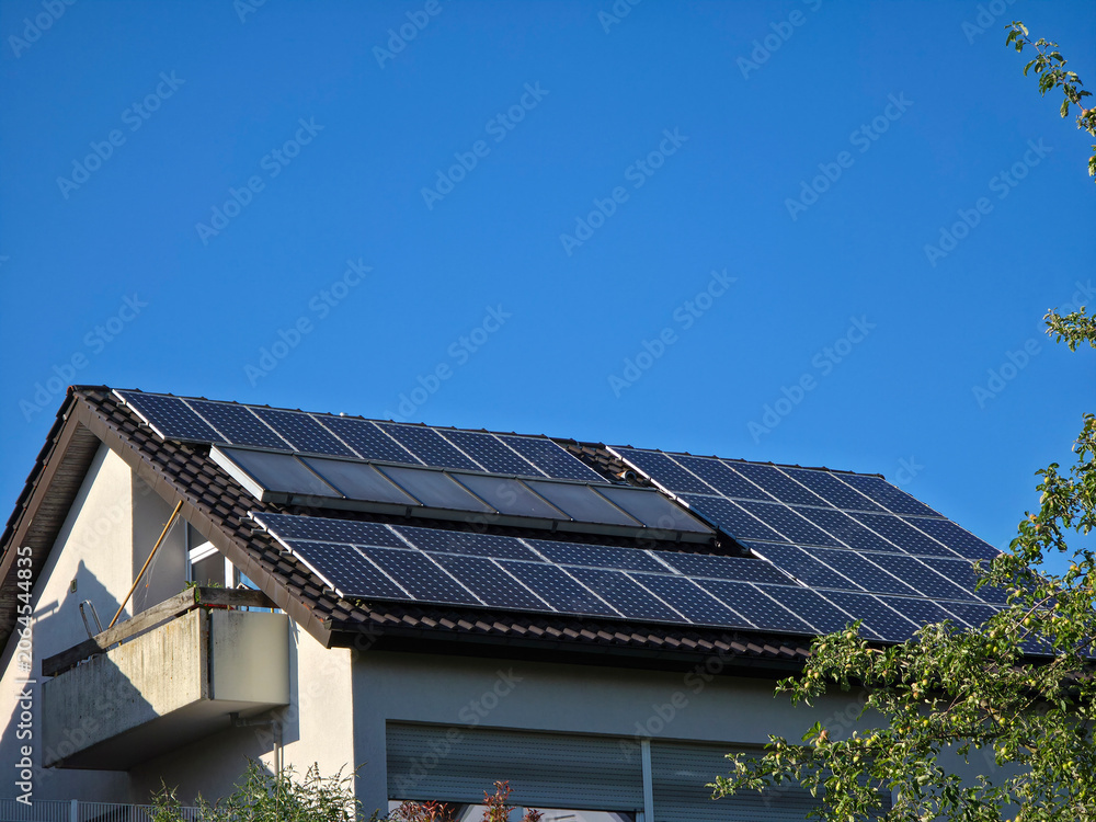 Fototapeta premium house roof fully covered with pv modules representing maximum solar efficiency beneath clear blue sky