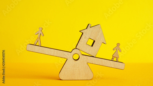 House balances between two people on a seesaw for property division.