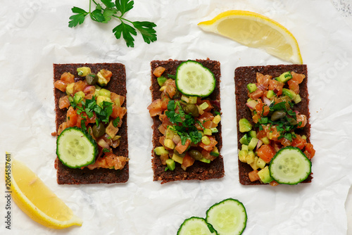 Принти на полотні Salmon tartare with avocado and cucumber on pumpernickel rye bread