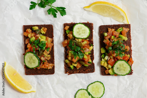 Salmon tartare with avocado and cucumber on pumpernickel rye bread.