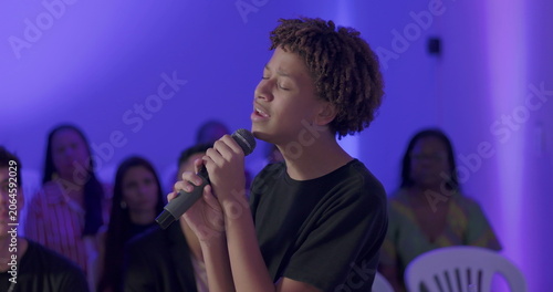 Fotografie Young African American teenager singing passionately with microphone during Chri