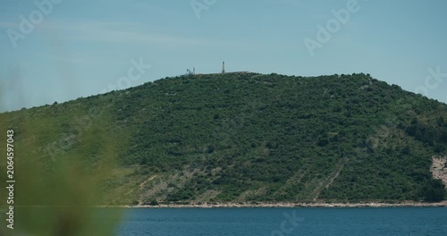 A coastal hill featuring the Our Lady of Loreto monument overlooks the Adriatic Sea near Primosten Croatia.
