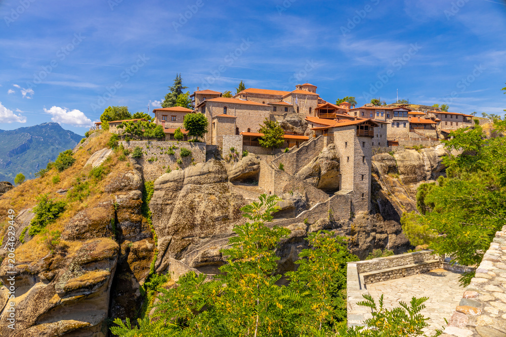 Fototapeta premium Historic monasteries of Meteora perched atop towering sandstone rock pillars in central Greece. Built by Orthodox monks centuries ago, these remarkable religious structures stand dramatically