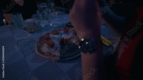 Prosciutto pizza served on a restaurant table with people dining in Zagreb, Croatia.
