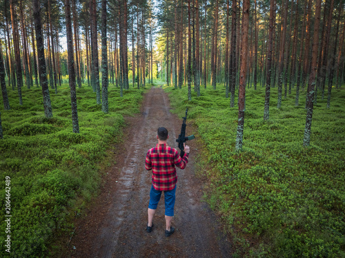 Fotografie Aerial drone view of man in red plaid flannel lumberjack shirt holding rifle wit