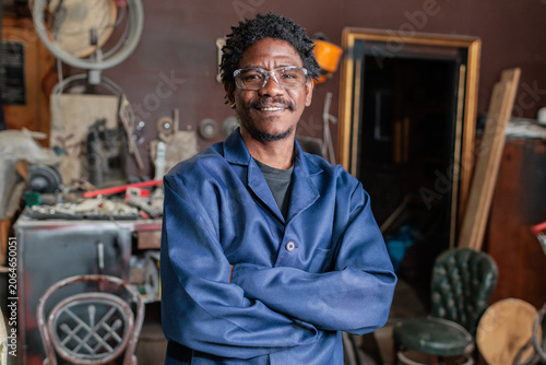 Smiling African worker stands in workshop with tools after successful working day