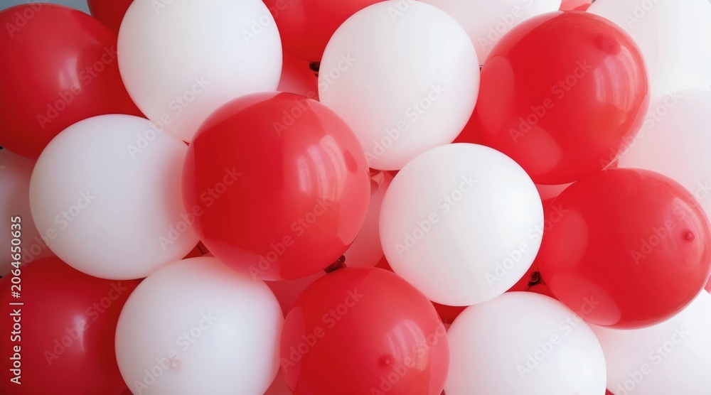 Fototapeta premium Many red and white balloons cluster together. Spheres create a round pattern. Dense, packed, festive decor fills the frame. Bright colors, geometric design, celebration background.