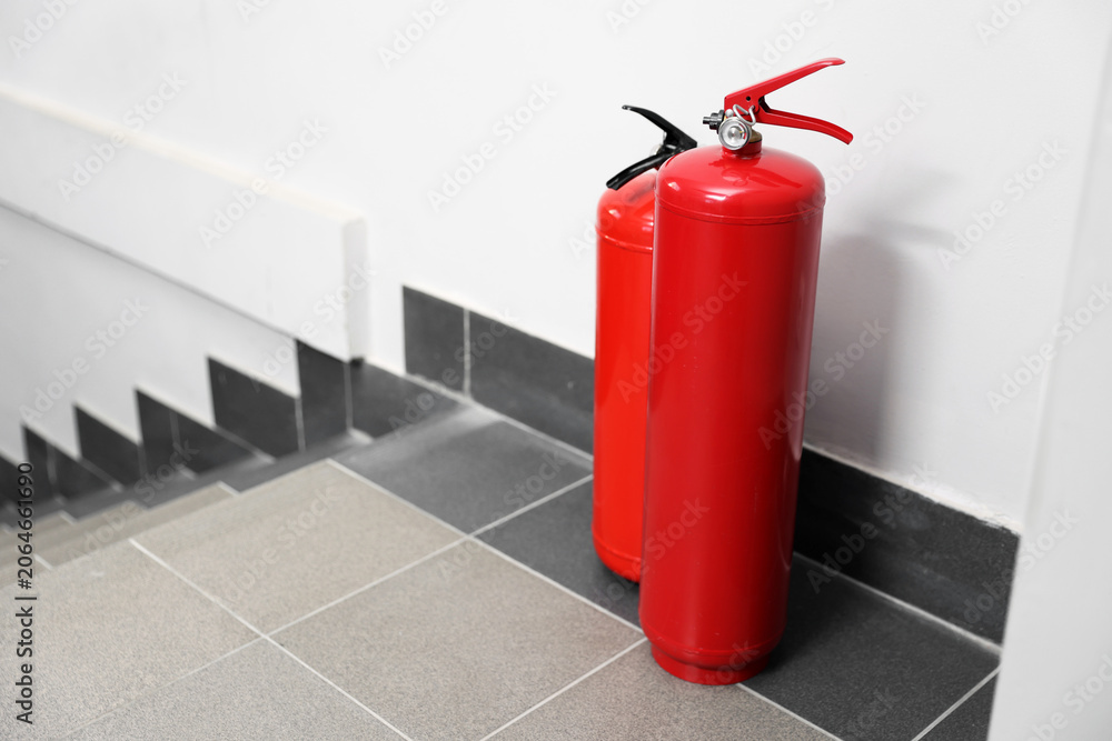 Obraz premium Two red fire extinguishers near white wall indoors, space for text