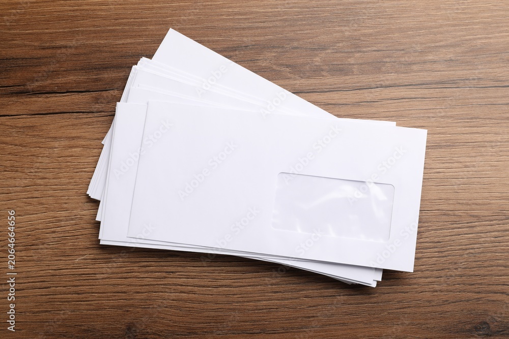Fototapeta premium Stack of white envelopes on wooden table, top view