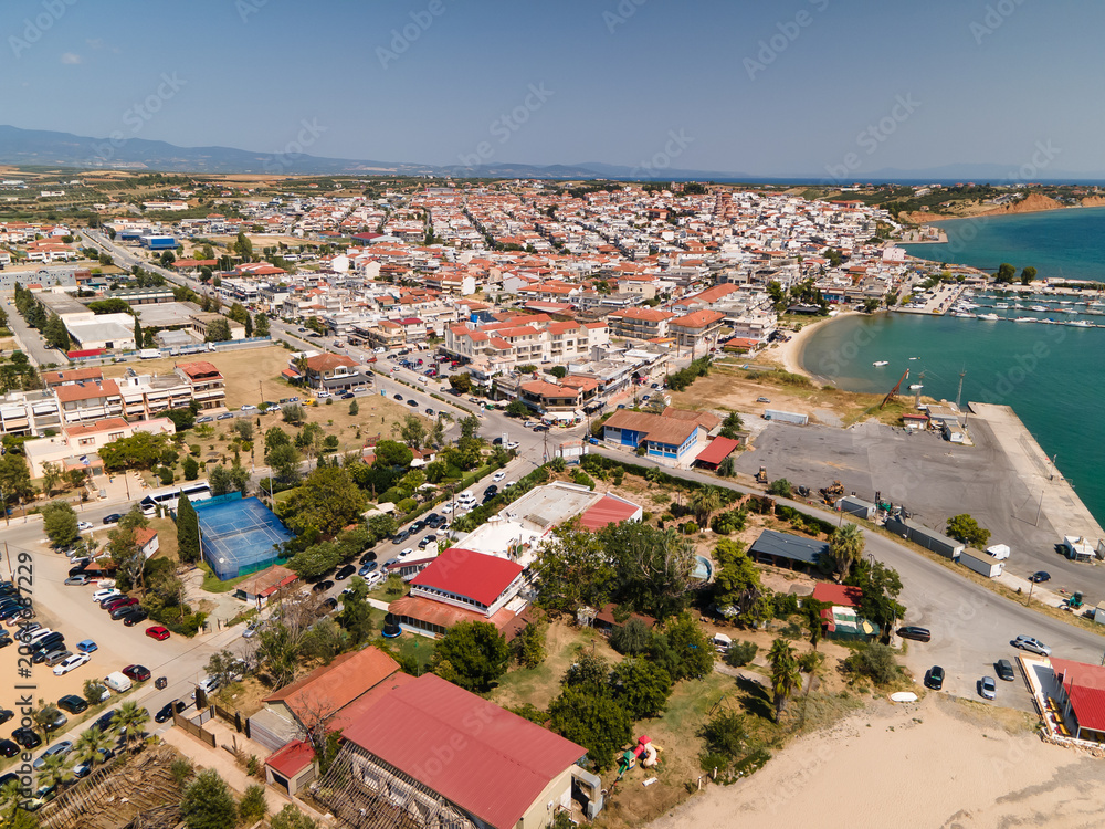 Naklejka premium Nea Moudania marina port, embankment and city, hotels and church in Halkidiki, Greece. Aerial panoramic drone view from above, top view from drone. Summer holidays Europe