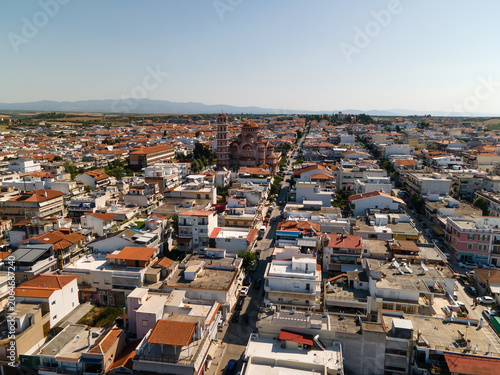Nea Moudania embankment and city, hotels and church in Halkidiki, Greece. Aerial panoramic drone view from above, top view from drone. Summer holidays Europe. Incredible clear blue water.