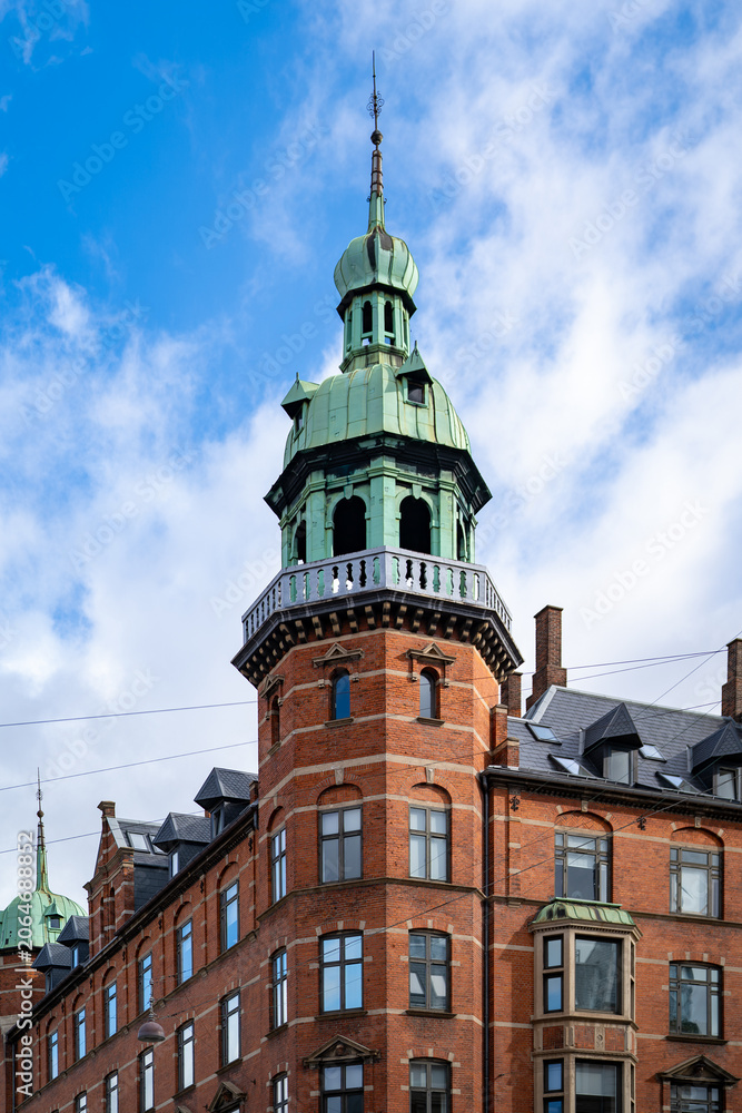 Obraz premium Historic red brick tower with green copper dome against blue sky