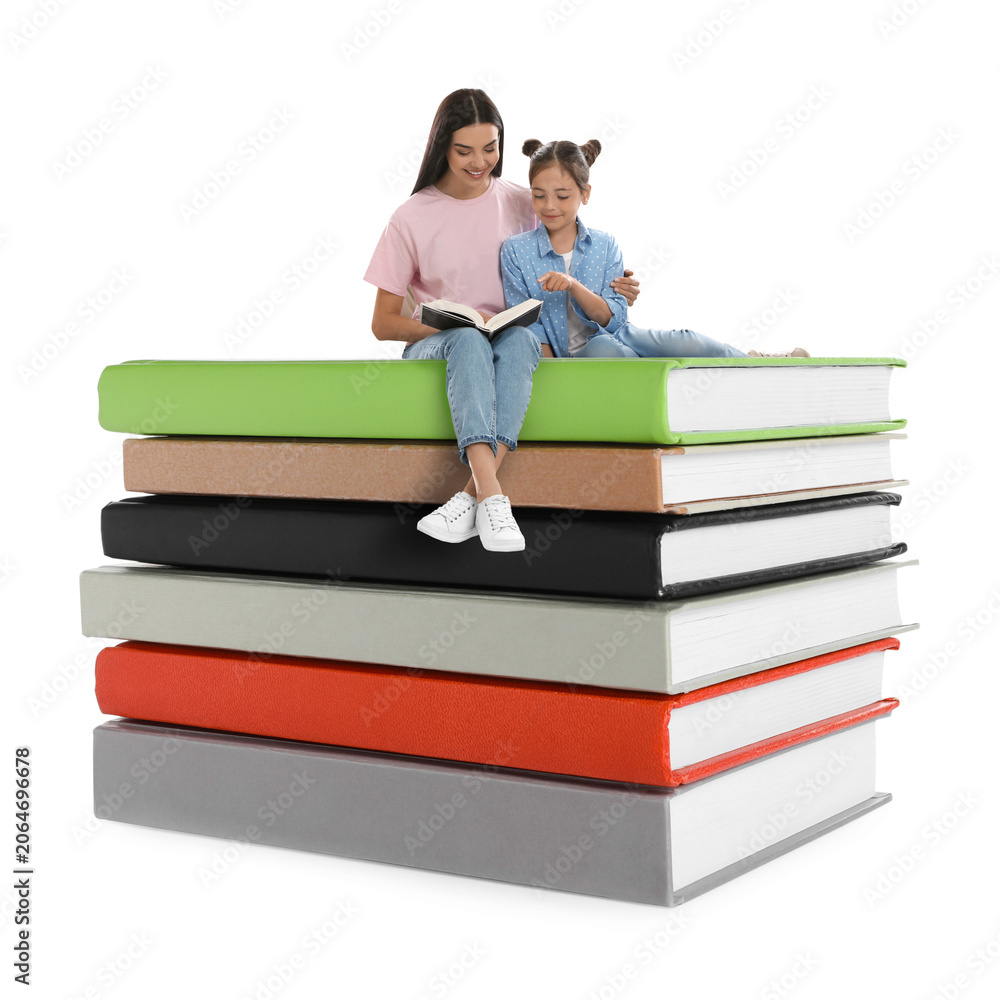 Naklejka premium Mother and daughter reading while sitting on stack of books against white background