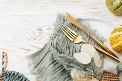 Φωτογραφία Close-up of fall table decor with green fabric napkin, golden cutlery, striped g