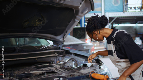Foto Licensed engineer in auto repair shop using virtual reality goggles to visualize car performance parameters, woman wearing modern vr headset while working on damaged vehicle, dolly in shot