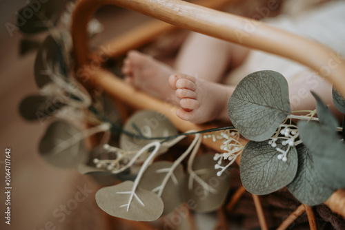Petits pieds de nouveau-né dans un berceau en rotin décoré de feuillage
