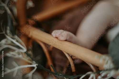 Petits pieds de nouveau-né dans un berceau en rotin décoré de feuillage