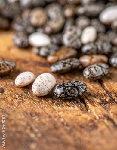 Macro close-up of dark and light chia seeds resting on a textured wooden surface, raw organic superfood, healthy eating ingredients, dietary nutrition.