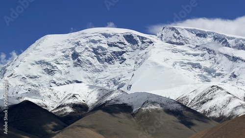 Snow-draped summit of Mt. Muztagh Ata dominates the rugged Karakoram landscape of Xinjiang, China.