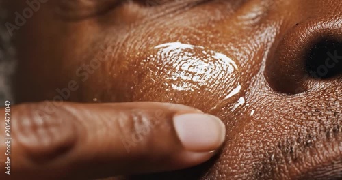 Woman applying golden serum to face skin for anti aging beauty treatment