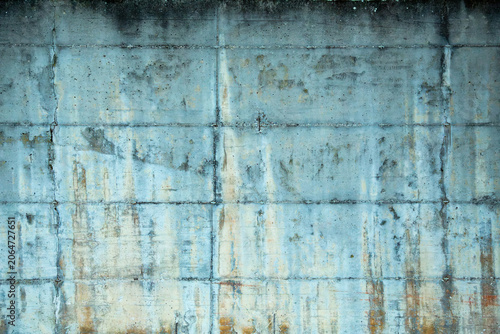This professional close up outdoor photograph captures the detailed and weathered texture of a solid concrete wall. The camera focuses straight on the industrial surface revealing deep cracks
