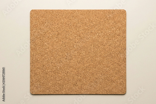 Blank square textured cork board mat on a beige background