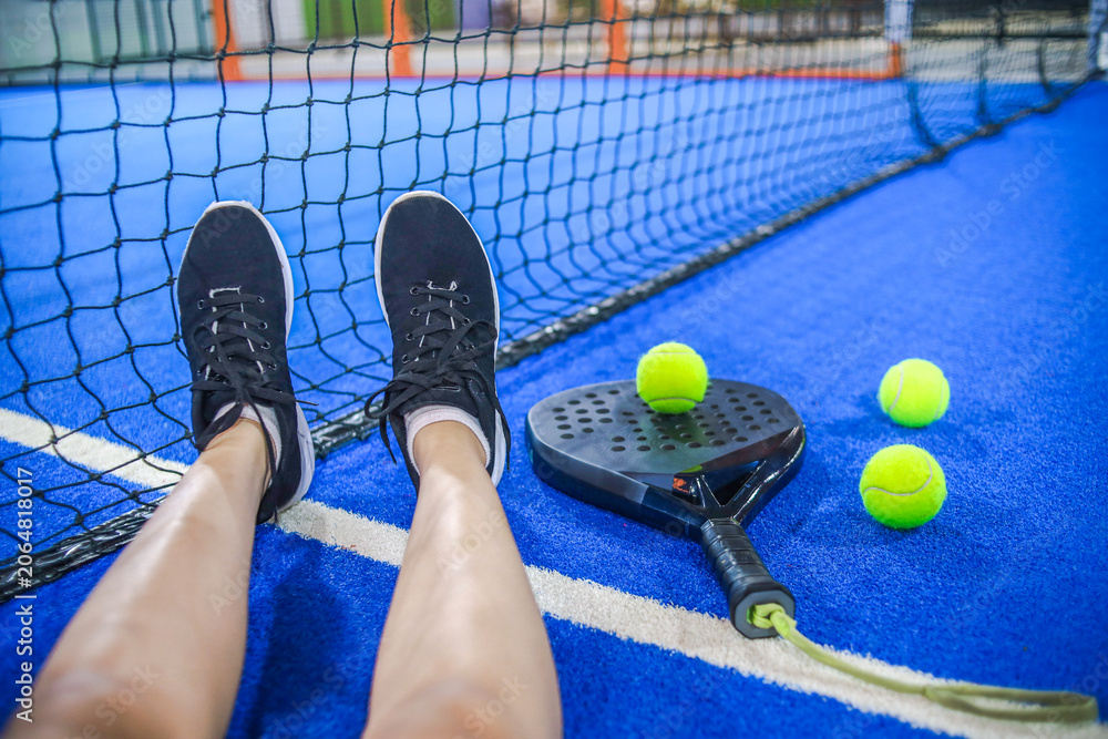 Naklejka premium Point of View of Player Resting Legs Against Net on Blue Padel Court