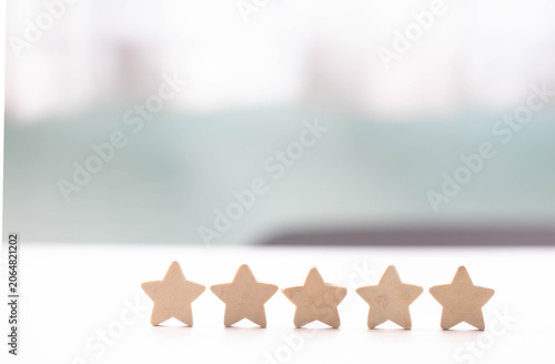 Five star rating review customer feedback satisfaction quality service reputation evaluation wooden star row white table, minimal background, bright light, positive satisfaction concept with copy