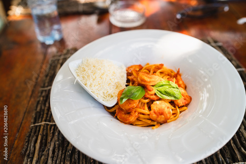 Delicious Italian pasta with shrimp and tomato sauce served outdoors.