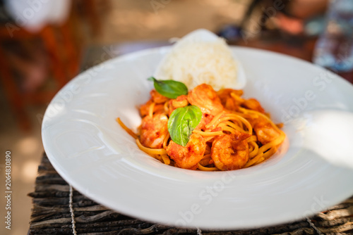 Delicious Italian pasta with shrimp and tomato sauce served outdoors.